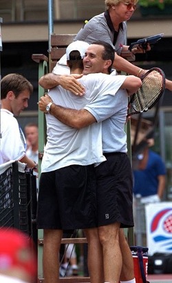 Tennis players hugging near an umpire